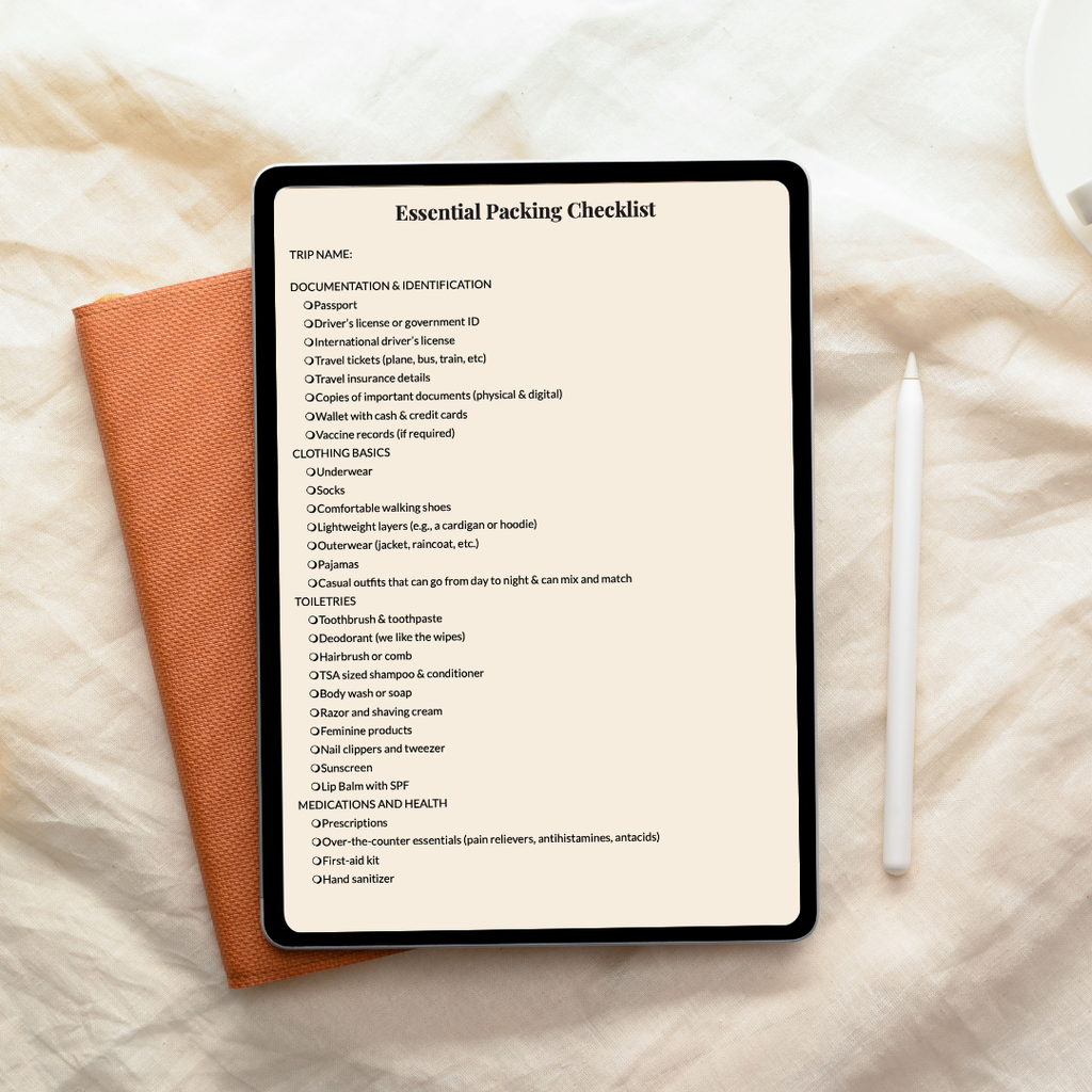 Tablet displaying an 'Essential Packing Checklist' on a textured surface with a pen and notebook.